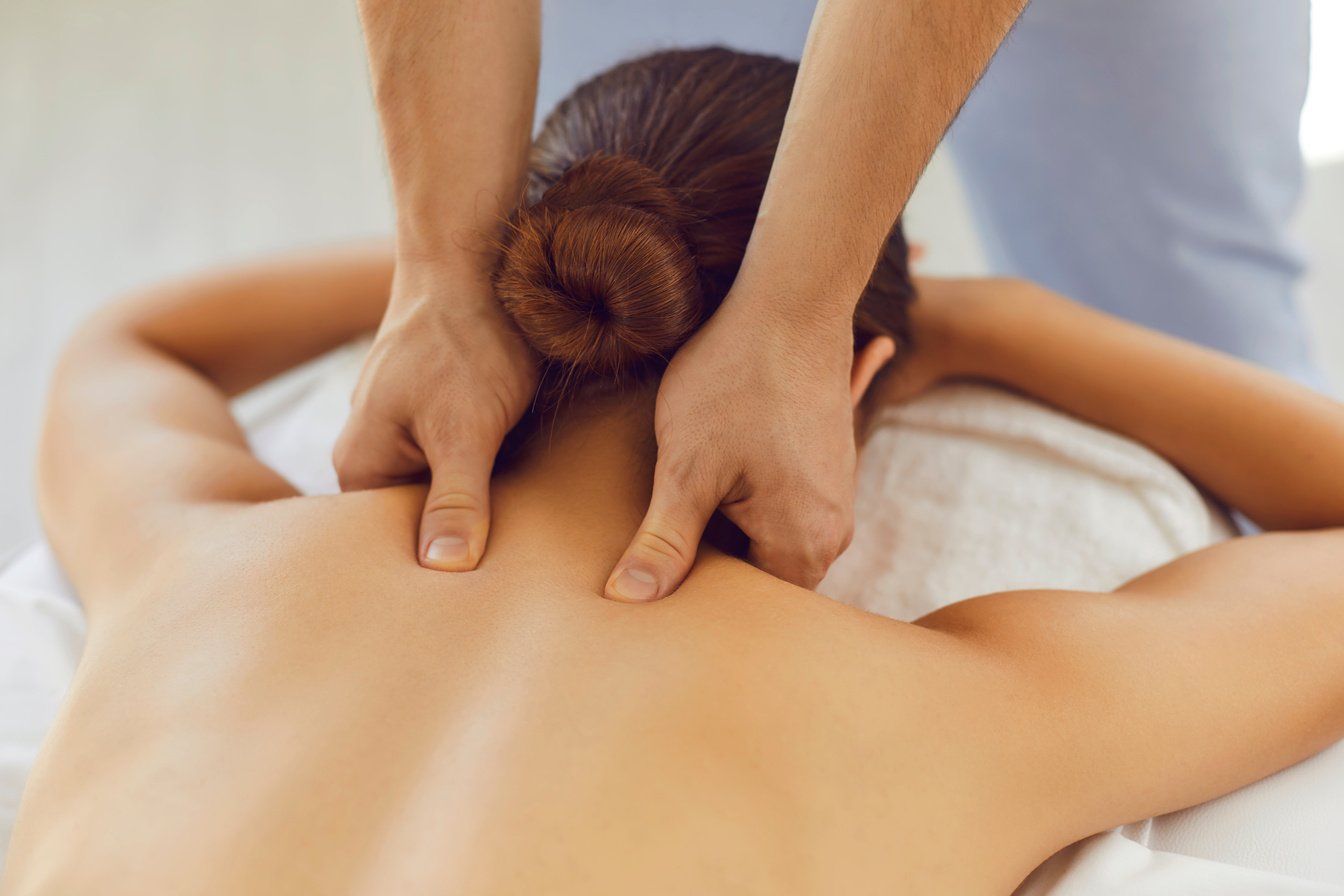 imagen que muestra una mujer a la que un fisioterapeuta le esta haciendo un masaje de espalda descontracturante.